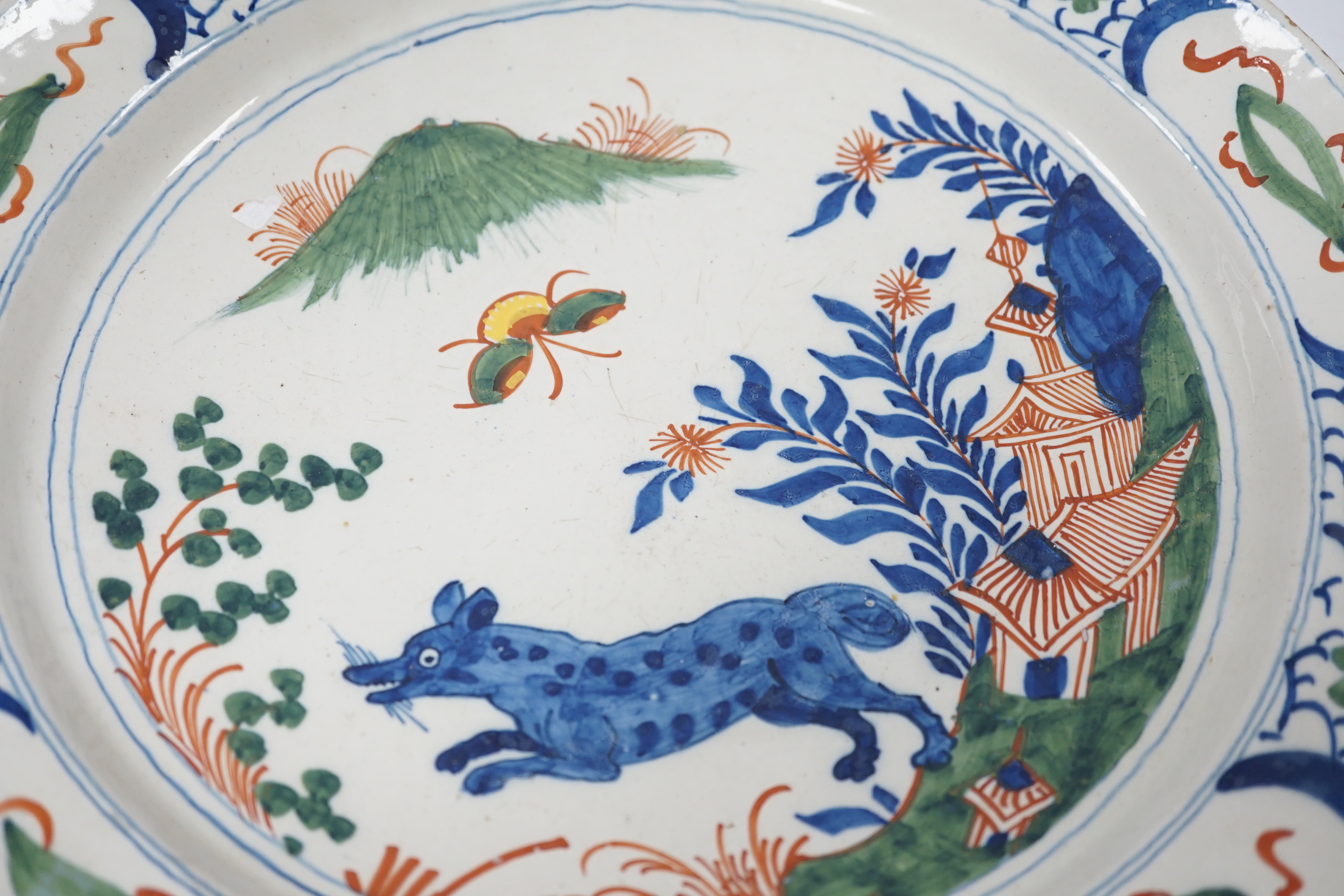 An 18th century delftware dish, the centre painted with a wolf, a bee and a pavilion, 35cm